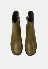 Botas de tobillo de cuero verde oliva con superficie lisa, punteras redondeadas y cremalleras laterales. Las suelas de goma negras mejoran la durabilidad.