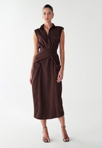 Robe boutonnée marron avec des manches courtes, une ceinture à la taille, deux poches avant et une longueur midi. Texture lisse, fabriquée en tissu.