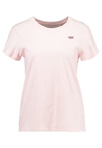 Różowa koszulka bawełniana z okrągłym dekoltem, krótkimi rękawami oraz małą czerwoną metką z logo na lewej piersi. Miękka tkanina i luźny krój.
