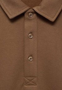 Braunes Polo-Shirt mit Kragen, drei Knöpfen und strukturiertem Stoff. Auffälliges Detail ist ein gestickter Logo-Bereich.