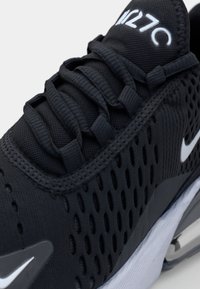 Svart Nike Air Max 270-sneaker med mesh-överdel, detaljerade snören, vit mellansula och synlig häl-luftkudde.