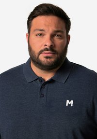 Navyblaue Poloshirt mit strukturiertem Stoff, drei Knöpfen und einem weißen Logo auf der linken Brust. Kurze Ärmel und ein klassisches Kragendesign.