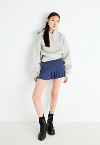 Gray hoodie with a relaxed fit, blue mini skirt with pleats, and black lace-up combat boots. Smooth fabric with subtle stretch.