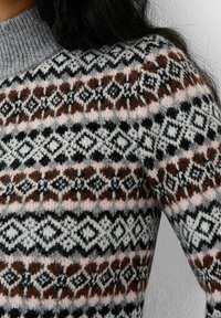 Stickad tröja med en blandning av grått, brunt, svart och rosa i en diamant- och geometrisk mönstring med en ribbad grå krage.