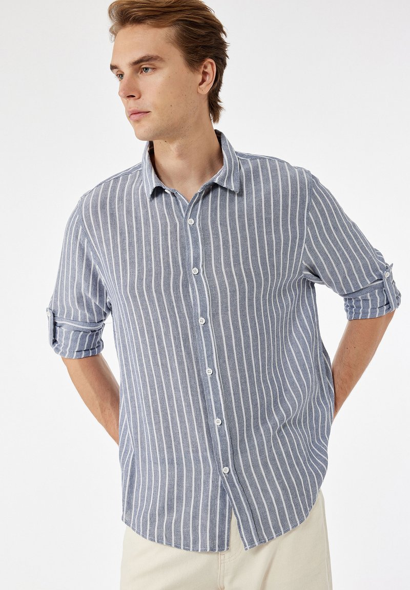 Lichtblauw en wit gestreept overhemd met knopen, voorzien van een spread collar, opgerolde mouwen en een relaxte pasvorm, gemaakt van ademend materiaal.