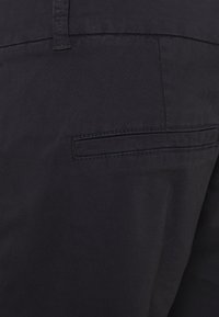Marineblauwe stoffen broek met een gladde textuur, voorzien van een enkele achterzak, met een rechte snit en subtiele stikdetails.