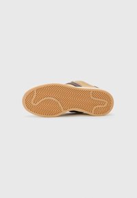 Shoe sole with a gum rubber texture featuring a zigzag pattern, brown leather accents, and a rounded shape.