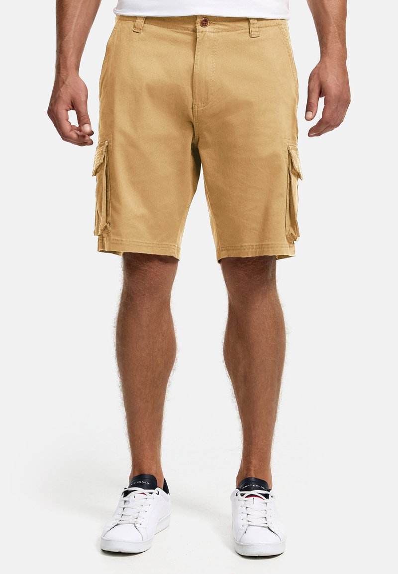 Beige Cargo-Shorts mit regular Fit, ausgestattet mit seitlichen Taschen, einem Knopfverschluss und einer glatten Baumwolltextur. Kombiniert mit weißen Sneakers.