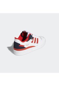 Baskets blanches Adidas avec des accents rouges et bleu marine, doublure intérieure rouge, trois bandes rouges sur le côté et logo Adidas au talon et à la semelle.