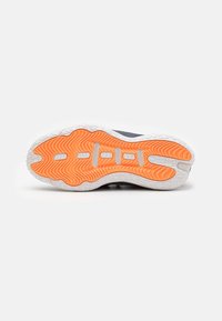 Semelle de chaussure tournée vers le haut avec une surface antidérapante texturée orange vif et des bords blancs, montrant un motif de bande de roulement détaillé et des découpes de ventilation.