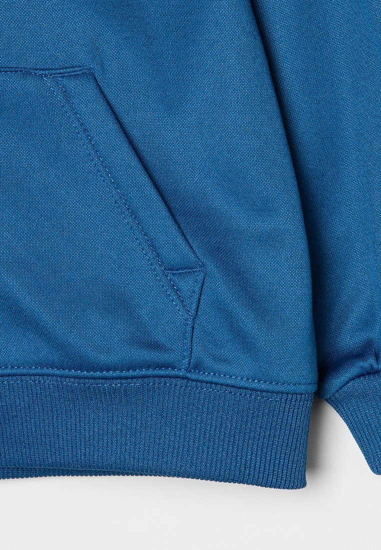 Sudadera azul texturizada con un bolsillo frontal y puños acanalados. El material es suave y tiene un ligero brillo.