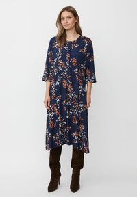 Mörkblå klänning med blommönster i orange, vitt och gr�önt. Har trekvartsärmar, rund halsringning och ett luftigt, flödande snitt.