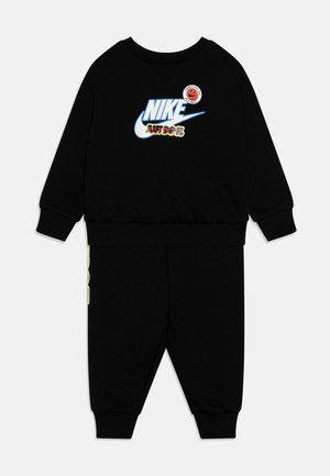Survêtement noir Nike composé de manches longues et de pantalons. Le graphique avant inclut "NIKE" et "JUST DO IT" avec des accents bleu, vert et rouge.