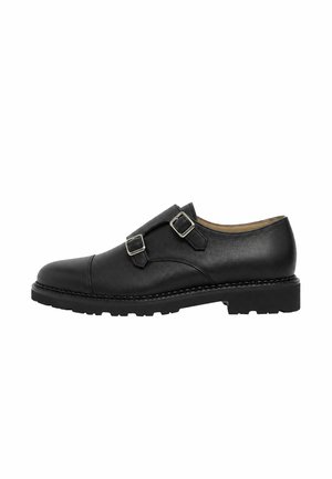 Chaussure en cuir noir à double boucle monk avec deux boucles argentées et une semelle basse et robuste, vue de profil sur fond blanc.