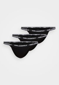 Tri čierne tangá z ľahkej látky. Každé má biely elastický pás s opakujúcim sa nápisom "KARL LAGERFELD".