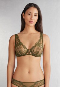 Olijfgroene kant bralette met doorschijnende bloemenpatronen. Bevat een V-hals en smalle bandjes, gecombineerd met bijpassende kanten string.