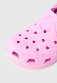 Sabot léger rose avec plusieurs trous de ventilation circulaires et une surface texturée, présenté en gros plan sur fond blanc.
