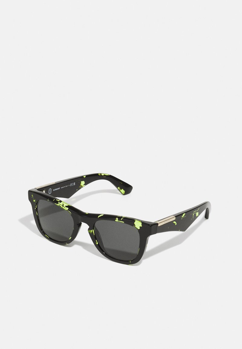 Ochelari de soare negri cu un model de stropi verzi. Cadru pătrat, lentile întunecate, accent de metal pe brate. Construcție din plastic ușor.