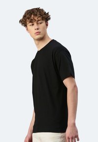 T-shirt in cotone nero con maniche corte e scollatura rotonda, caratterizzata da una vestibilità ampia e una superficie liscia.