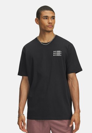 Black cotton t-shirt featuring a crew neck, short sleeves, and white printed logo details on the chest. Paired with mesh shorts.