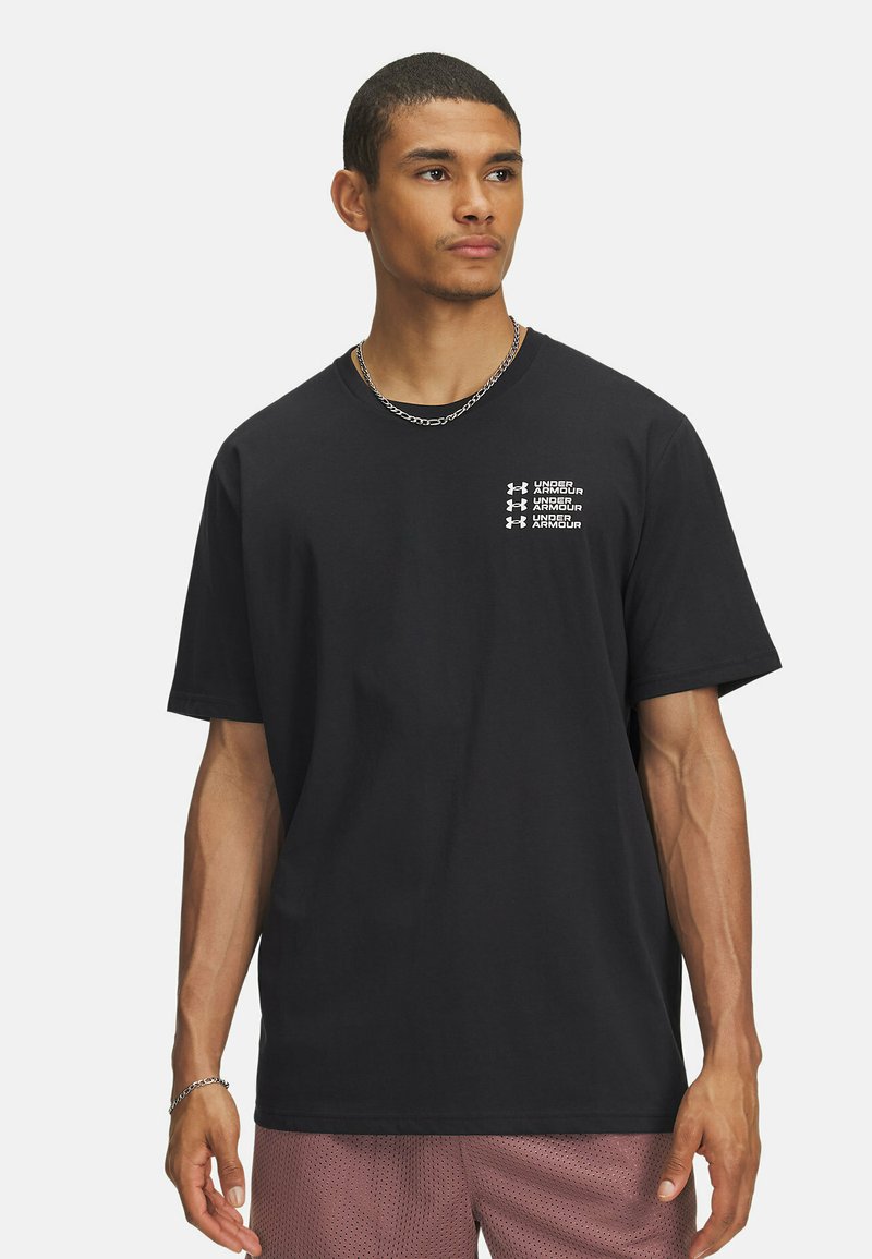 Schwarzes Baumwoll-T-Shirt mit Rundhalsausschnitt, kurzen Ärmeln und weißen bedruckten Logo-Details auf der Brust. Kombiniert mit Mesh-Shorts.