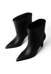 Bocanci negri din piele pentru gleznă cu vârf ascuțit, textură netedă și toc subțire de înălțime mare. Proiectați într-un stil minimalist, fără elemente de feronerie vizibile.