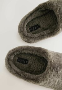 Szare, puszyste kapcie o miękkiej fakturze, okrągłym kształcie i metce z napisem "NEXT" wewnątrz. Posiadają pluszowe wnętrze.