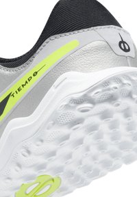 Scarpa sportiva grigia e nera con accenti gialli, tomaia sintetica testurizzata e suola bianca a motivi con dettagli che migliorano la presa.