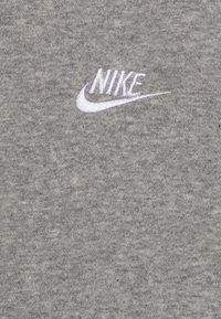 Siv sweatshirt iz mehkega materiala z izvezenim belim logotipom Nike na levi strani. Preprosta tekstura in dizajn.