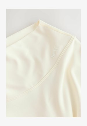 Top crem realizat dintr-un material neted și elastic, cu un decolteu larg și un logo discret în relief. Finisajul include cusături vizibile.