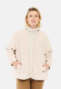 Beige fleeced jacket met een ronde hals, twee voorzakken, drukknoopsluiting en subtiele logo-afbeelding op de zak.