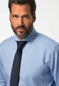 Světle modrá kostkovaná košile se strukturou límce, doplněná o tmavou jednobarevnou kravatu. Má hladkou texturu látky a přiléhavý střih.