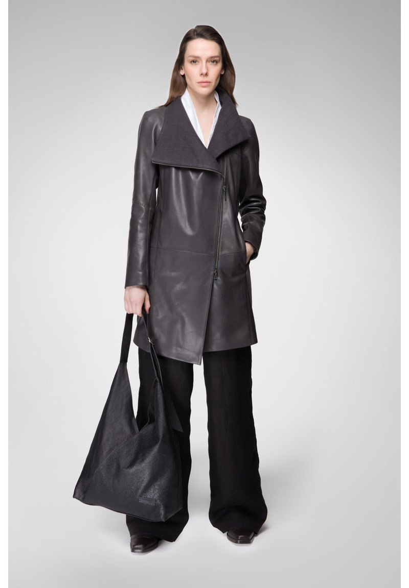 Grau Lederjacke mit großem Kragen, Frontreißverschluss und Taschen, kombiniert mit schwarzen weiten Hosen und einer schwarzen lässigen Tasche.