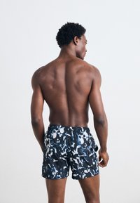 Badeshorts mit schwarzem Grundton und einem blauen und weißen abstrakten Muster, elastischem Bund mit Kordelzug und seitlichen Taschen.