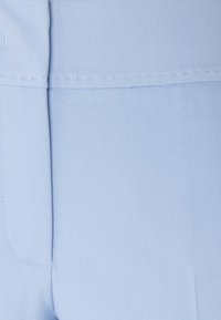 Ljusblått tyg med en slät textur, med stygn i en kontrasterande tråd längs kanterna och sömmarna.