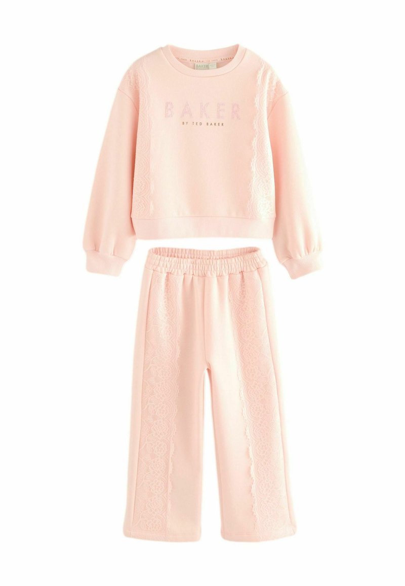 Ensemble de jogging rose clair comprenant un sweat cropped avec des détails en dentelle et un pantalon à jambes larges assorti avec une taille élastique.