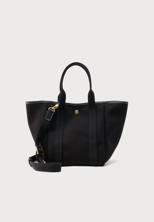 Bolso tote negro con dos asas y una correa de hombro ajustable, con herrajes en tono dorado y un pequeño emblema circular en la parte frontal.