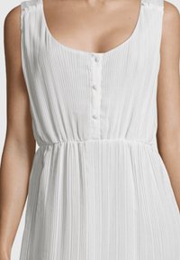 Vestido blanco con plisados, escote redondeado, botones en la parte delantera y una cintura elástica para un ajuste relajado. Tejido ligero con un acabado texturizado.