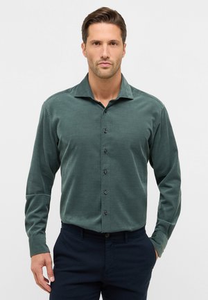 Langsleeve shirt in donkergroen, gemaakt van gestructureerde stof. Heeft een puntige kraag, zes zwarte knopen aan de voorkant en aansluitende manchetten.