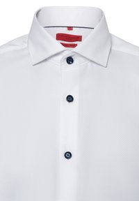 Witte, gestructureerde overhemden met een slim fit. Beschikt over een omgeslagen kraag, drie marineblauwe knopen en een rood label binnenin de kraag.