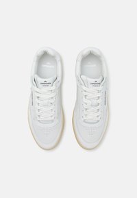 Sneaker atletiche bianche con dettagli perforati, lacci piatti e suola in gomma color talpa. Logo sulla linguetta e sul pannello laterale.