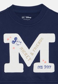 Marineblaue Baby-Sweatshirt mit großem weißen "M", Mickey-Maus-Gesicht, dem Schriftzug "MICKEY & FRIENDS", roten Sternen und "OH BOY"-Schriftzug auf der Vorderseite.
