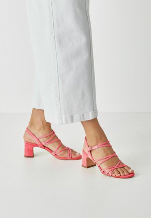 Roze suède sandalen met hak, voorzien van kruisbandjes en een vierkante blokhak. Open teen ontwerp, gladde textuur en verstelbare enkelriem.