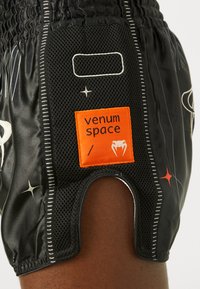 Schwarze Sportshorts mit Netzeinsätzen, ausgestattet mit einem auffälligen orangefarbenen Label mit der Aufschrift "venum space" und weißen Akzenten mit Sternmuster.