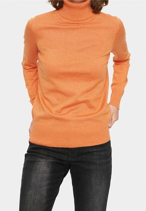 Pull à col roulé orange en tricot doux, avec des manches longues et une coupe ajustée. Associé à un jean foncé.