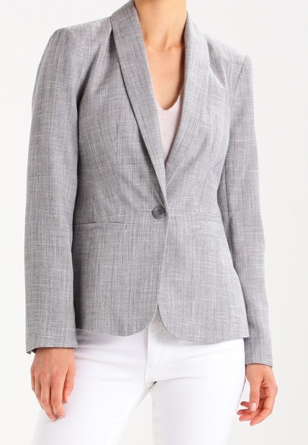 Šedý strukturovaný blazer s elegantním střihem, zapínáním na jeden knoflík a klopami. Nosený přes světlejší top a kombinovaný s bílými kalhotami.