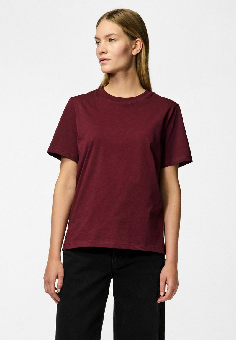 Burgunderfarget bomulls T-skjorte med korte ermer, rund hals og avslappet passform. Stoffet ser jevnt og uornert ut, uten synlige mønstre eller detaljer.