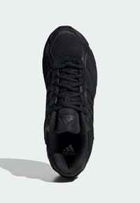 Chaussure de sport noire avec des textures en mesh et en daim, dotée de lacets plats, d'un col rembourré et de trois rayures caractéristiques sur le côté.