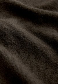 Brunt tekstureret stof med et ribbet mønster, der viser bløde, ujævne draperinger og en let glans, hvilket understreger dets varme og dybde.