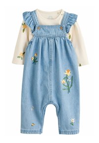 Salopette en denim avec des motifs floraux brodés ; tissu bleu clair, bretelles volantées et une chemise à manches longues crème en dessous.